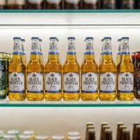 Linha de cervejas Black Princess em garrafas e latas na prateleira, incluindo variações como IPA e Black Princess Zero.