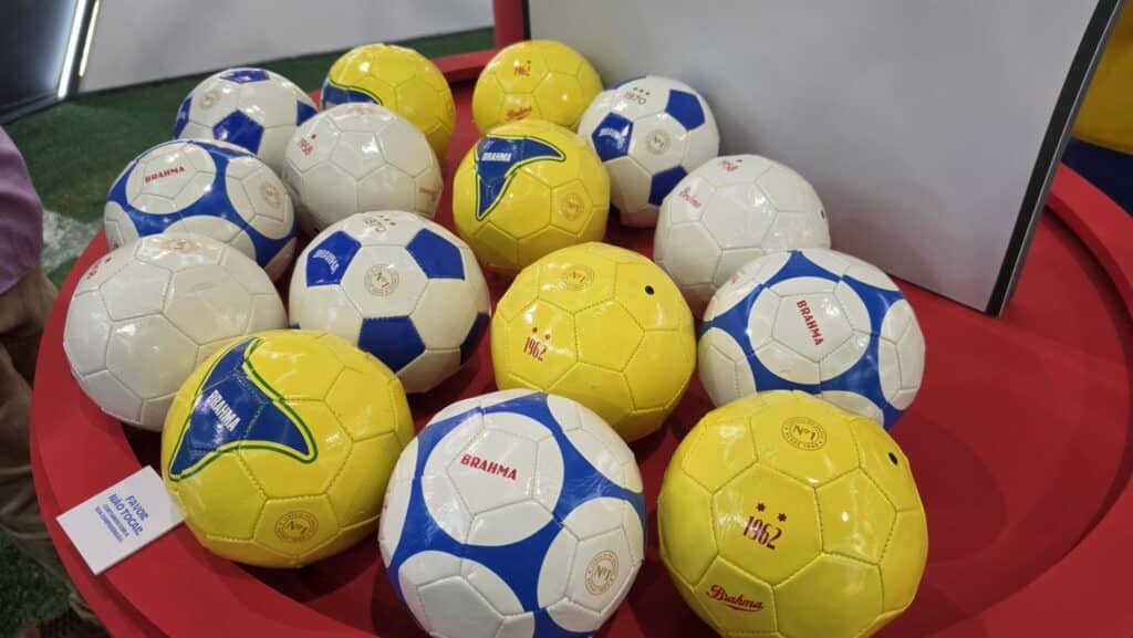 Bolas colecionáveis da Brahma em exposição, com cores branco, azul e amarelo, em ambiente de evento.