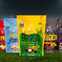 Embalagens da linha Cacau Show Bytes com temas de países da Copa do Mundo, incluindo Brasil, na frente de um estádio