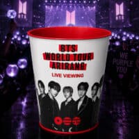 Balde colecionável do BTS com a arte “ARIRANG Live Viewing”, em cenário roxo do evento no Cinépolis.