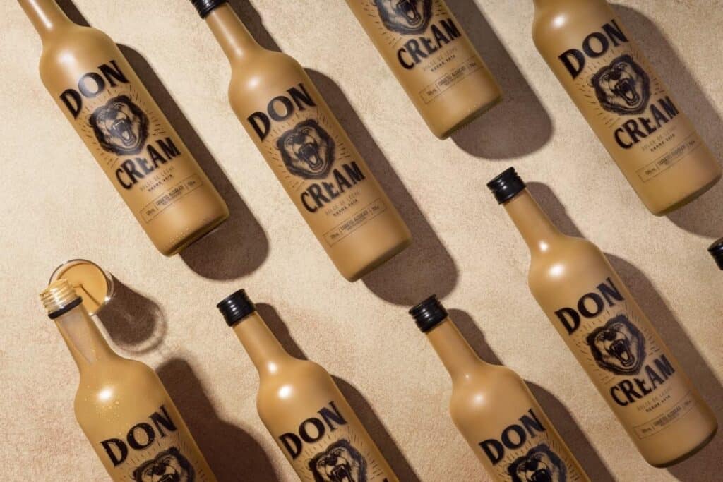 Garrafinhas do produto Don Cream com rótulo “DON CREAM” em fundo claro, em composição repetida.