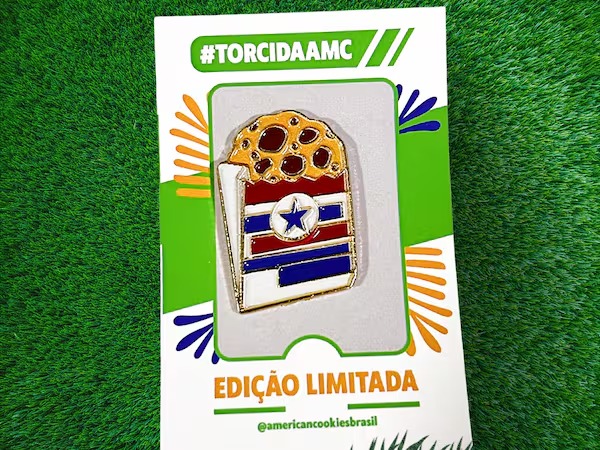 Embalagem de American Cookies na grama com texto “#TORCIDAA MC” e “EDIÇÃO LIMITADA”, cookie com bandeira dos EUA e estrela