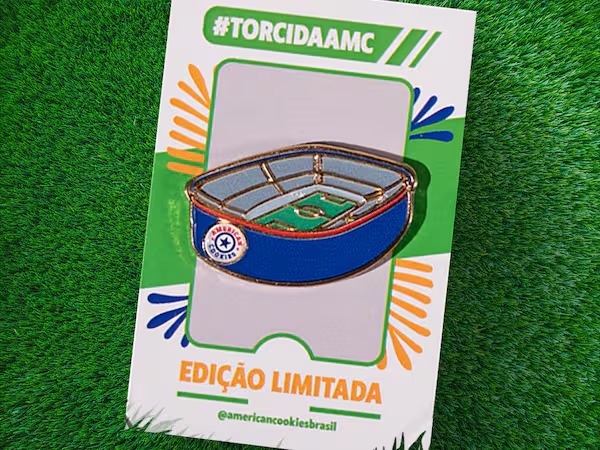 Embale de cookie Edição Limitada #TORCIDAAMC em fundo de grama, com emblema do estádio e bandeiras alusivas à Copa do Mundo.