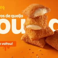 Popeyes anuncia retorno dos travesseiros de queijo gouda: imagem com salgados empilhados e fundo laranja.