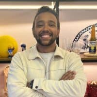 Homem sorridente em escritório, com bolas e objetos decorativos ao fundo, em foto relacionada à Mood Group.