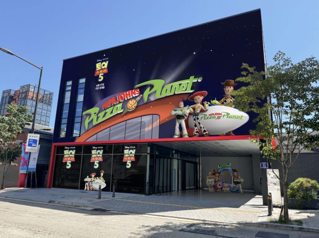Fachada de pop-up da Papa Johns com temática do Pizza Planet e personagens de Toy Story 5 em Seul