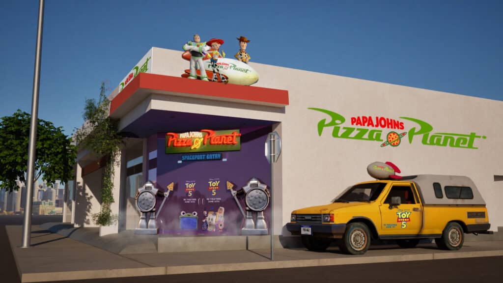 Fachada do Pizza Planet da Papa Johns com ônibus amarelo e cenário temático do Toy Story 5 em Los Angeles.