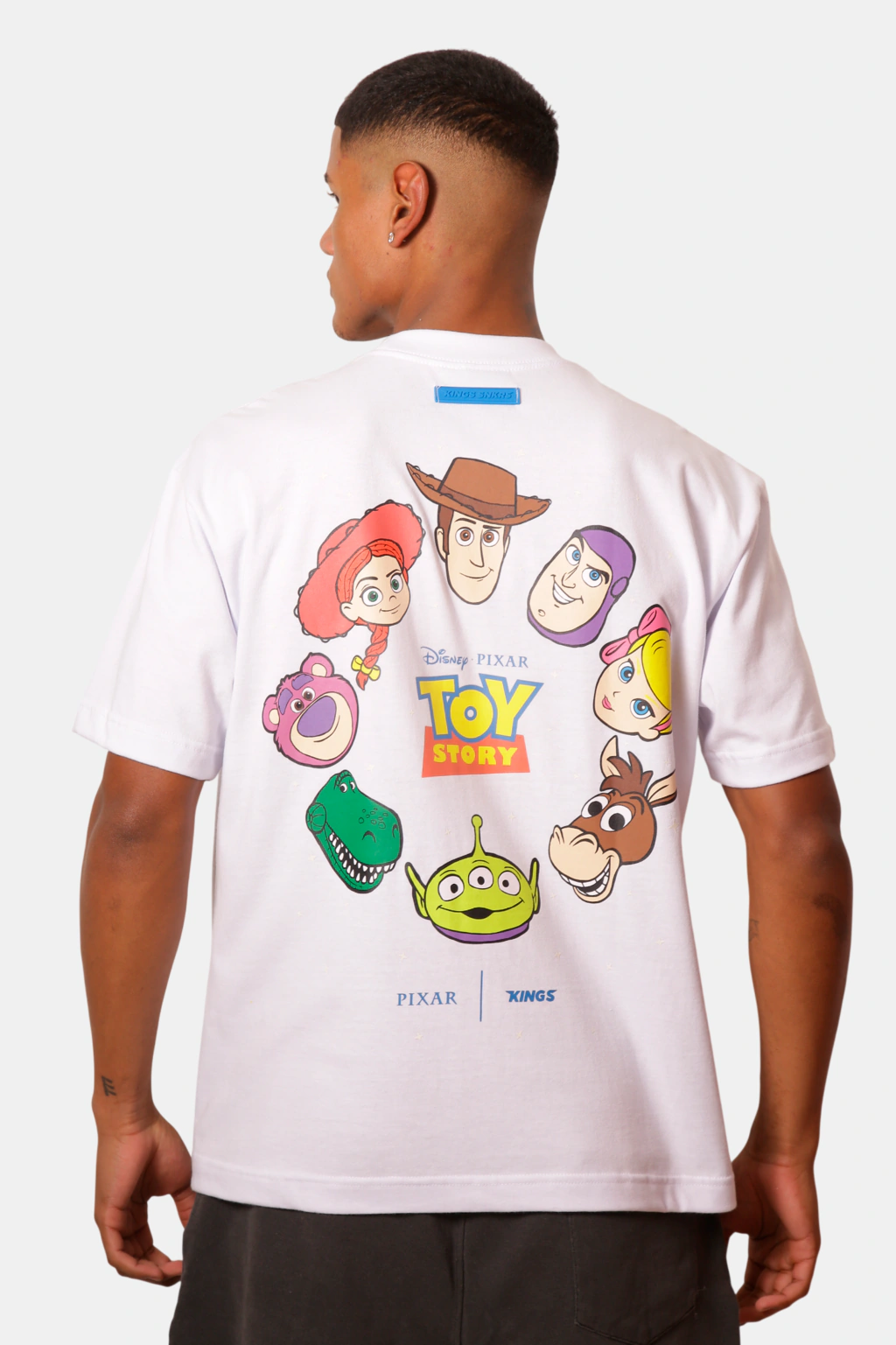 Camiseta branca da coleção Kings com estampa do Toy Story 5, vista de costas do modelo, com personagens da Pixar.