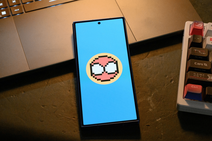 Smartphone exibindo um ícone de aranha pixelado em tela azul, em evento do Spidey Tracker da Samsung