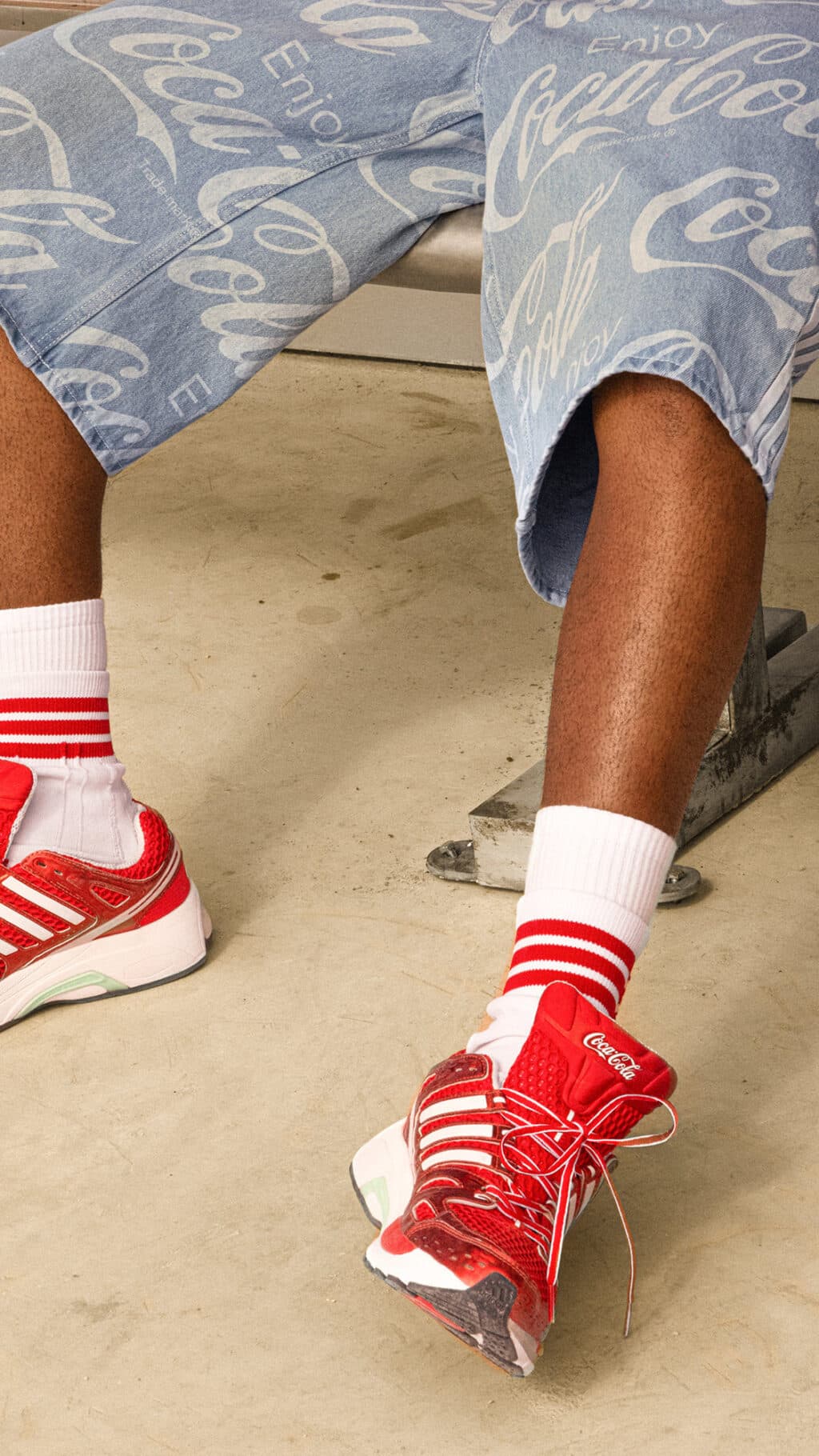 Pés com meias listradas e tênis vermelho Coca-Cola com estampa em coleção Adidas Originals para a Copa do Mundo