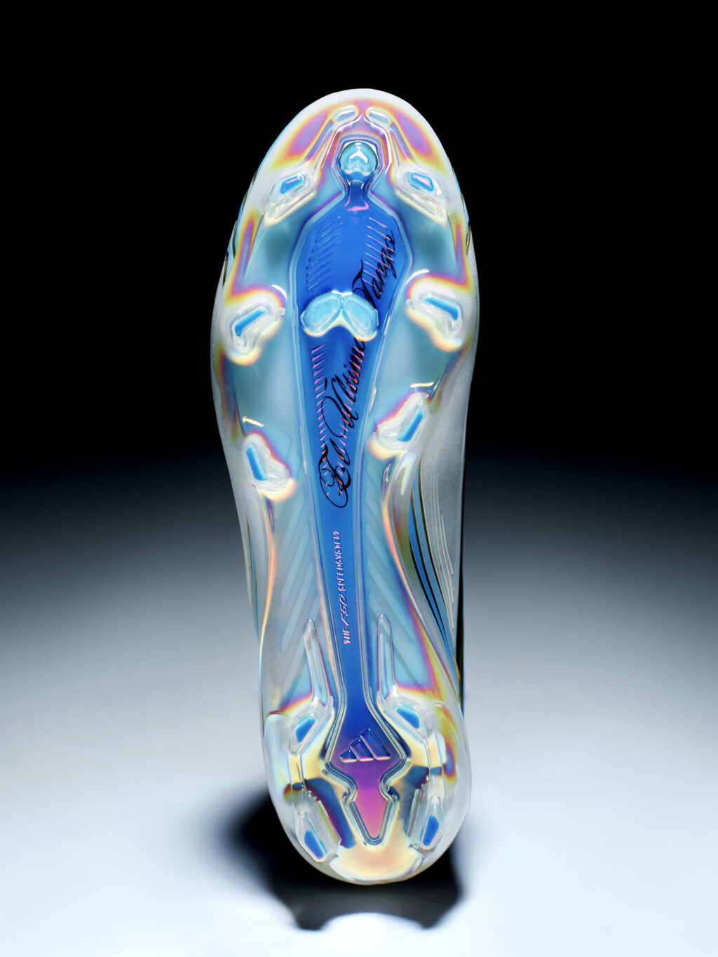 Chuteira Adidas da coleção 'El Último Tango' com design azul e prateado, vista de costas, em fundo escuro e iluminação de estúdio.