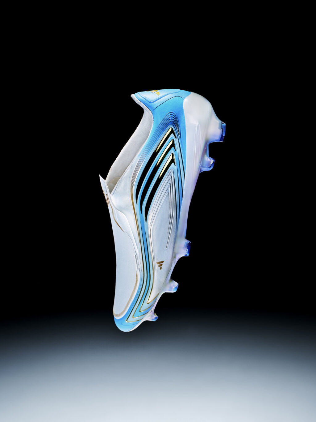 Chuteira de futebol Adidas Messi, branca com detalhes azuis e dourados, em fundo preto