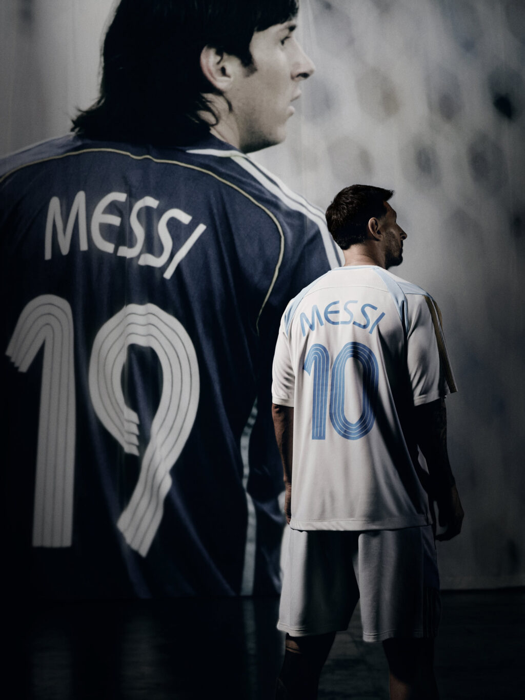 Lionel Messi em campo com camisa preta e outra com as costas escrito Messi e número 10, em foto promocional da Adidas.