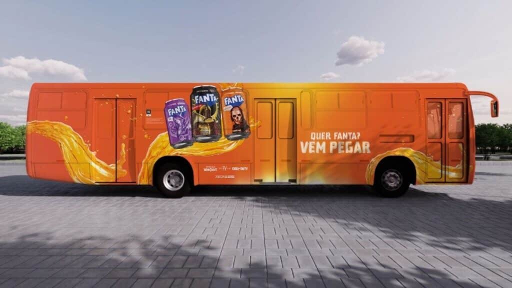 Ativação Fanta em ônibus laranja itinerante Ônibus laranja da ativação Fanta com campanhas e embalagens na lateral, em cenário aberto ao ar livre.