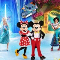 Personagens do espetáculo Disney On Ice em cena no gelo, com Minnie, Mickey e Stitch ao fundo