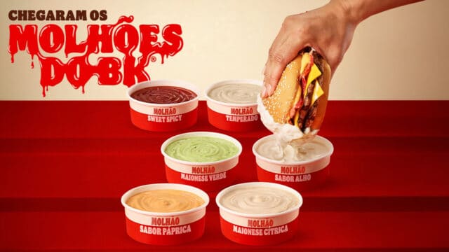 Imagem promocional dos Molhões do BK, com seis potes de molhos do Burger King e uma mão mergulhando um sanduíche