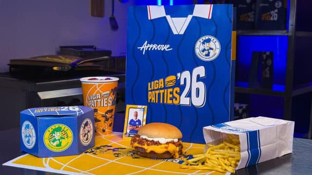 Sanduíche e batatas em embalagem da Liga Patties 2026, com caixa e copo ao lado, em cenário de Copa do Mundo.