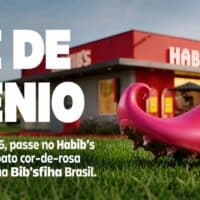 Chuteira cor-de-rosa do Habib’s sobre grama com fachada da loja ao fundo e texto promocional em destaque.