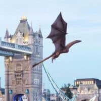 Syrax em voo sobre Londres, com o dragão próximo à Tower Bridge durante ação promocional do HBO Max