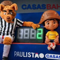 Mascotes do Paulistão e Casas Bahia ao lado de placa digital com 88, em cenário do campeonato em azul e listras