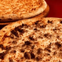 Duas pizzas com cobertura cremosa e pedaços tostados, sugerindo pizza de fondue.