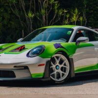 Porsche 911 inspirado em Buzz Lightyear, com pintura verde e branca e detalhes roxos, estacionado ao ar livre.