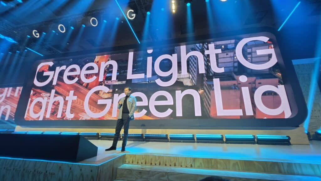 Palestra no palco com telão do evento Green Light, em ambiente de conferência com iluminação azul e tecnologia