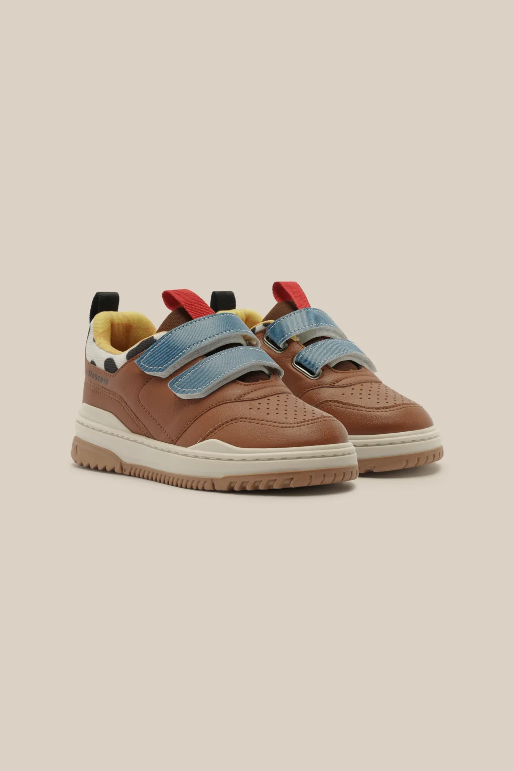 Tênis infantil estilo casual caramelo com detalhes azuis, palmilha e cadarços coloridos em fundo claro