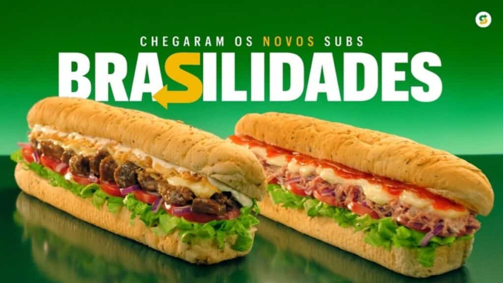 Imagem promocional do Subway Brasilidades com dois sanduíches ao fundo verde e o texto “BRASILIDADES”.