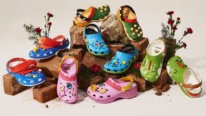 Crocs coloridas inspiradas em Super Mario Bros da Nintendo, com modelos azuis, verdes, vermelhos e rosa ao lado de flores.