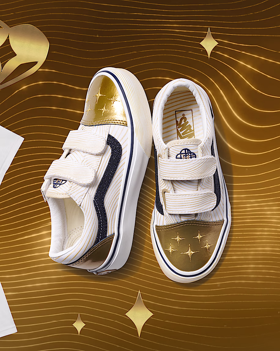 Tênis Vans Old Skool infantil branco e dourado, com estrelas e detalhes pretos, em fundo dourado com ondas