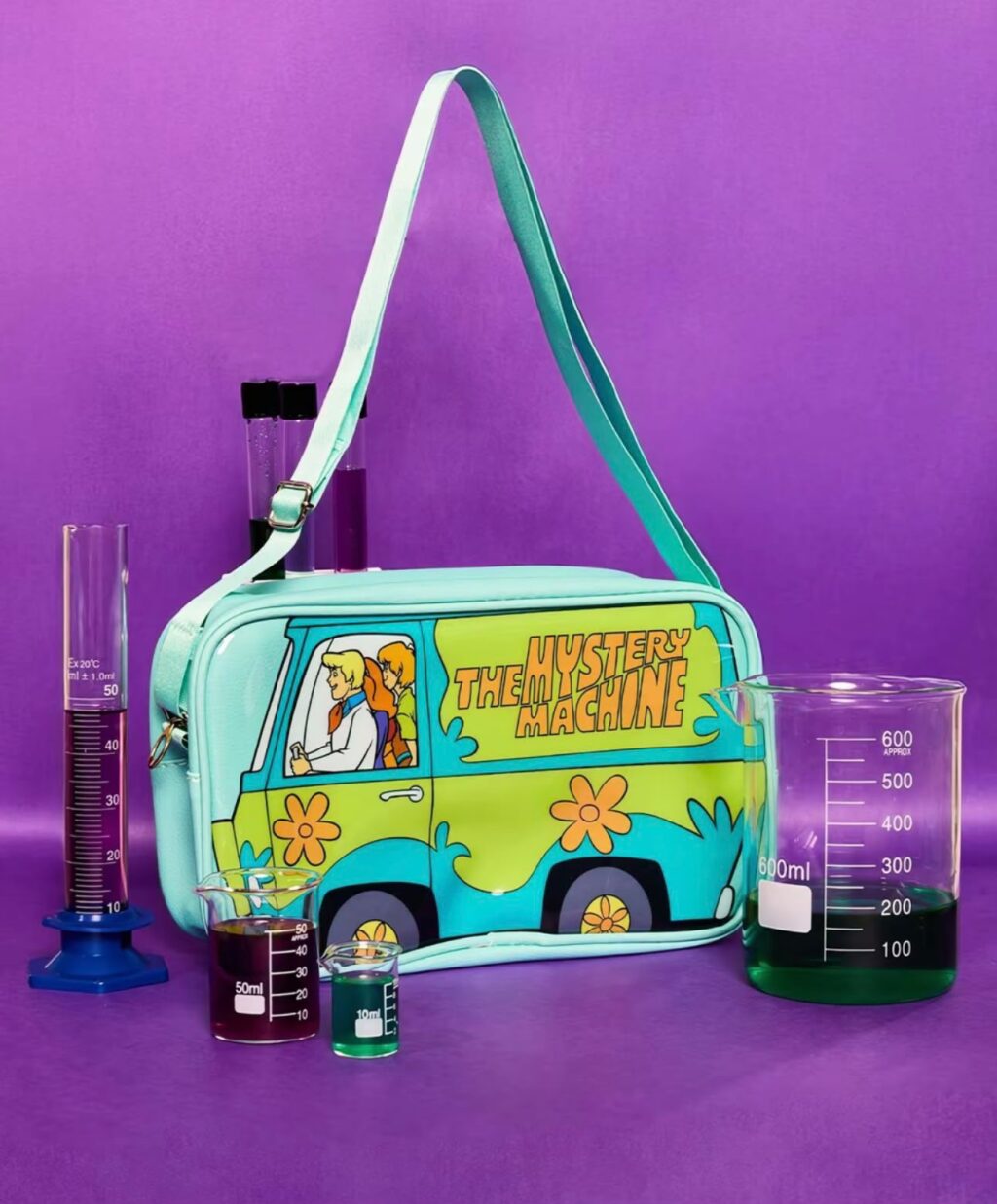 Bolsa de acessórios azul e verde da Mystery Machine, inspirada em Scooby-Doo, com estética colecionável sobre fundo roxo.