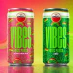 Duas latas Amstel Vibes Pride, uma rosa e outra verde, em fundo com gradiente colorido, com tema LGBTQIAPN+.