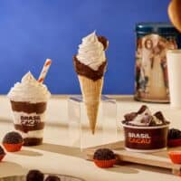 Sorvetes Brasil Cacau com destaque para Moça Brigadeiro em copos, com cones e sobremesas sobre mesa clara