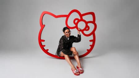 Zaxy com Hello Kitty and Friends: sandálias coloridas Modelo usando sandálias coloridas em um cenário com logo grande da Hello Kitty em fundo claro