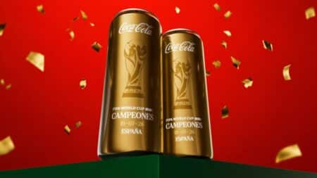 Coca-Cola latas douradas “Campeones España” edição limitada Duas latas douradas da Coca-Cola com a frase “Campeones España” em fundo vermelho com confetes.