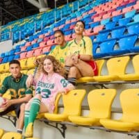 Torcedores posando em arquibancada de estádio com cadeiras coloridas, em campanha do concurso SHEIN