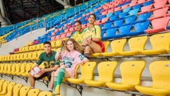 Concurso SHEIN: torcedores em arquibancada colorida Torcedores posando em arquibancada de estádio com cadeiras coloridas, em campanha do concurso SHEIN