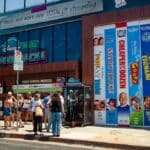 Fachada de pop-up da Disney+ e Hulu em Los Angeles, com painéis coloridos e pessoas em frente.