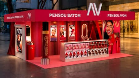 Banca de batons Avon “PENSOU BATOM” no Shopping Cidade São Paulo Avon “PENSOU BATOM” em banca temática no Shopping, com parede vermelha e fila de batons expostos para fotos