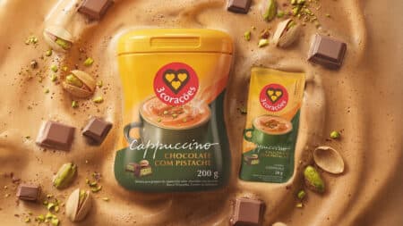 Embalagem de Cappuccino Chocolate com Pistache da 3 Corações, com pistaches e pedaços de chocolate ao fundo.