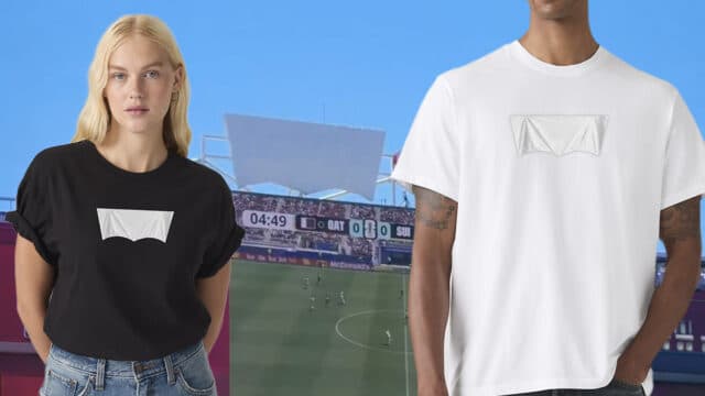 Modelo veste camiseta branca e preta com logo da Levi’s coberto, diante de estádio de futebol em dia de partida da Copa do Mundo.