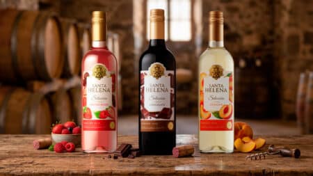 Garrafas Santa Helena Selección à base de vinho em sabores chocolate, frutas vermelhas e pêssego, sobre mesa de madeira.