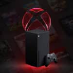 Ilustração de um Xbox preto com luz vermelha e controlador, em fundo desfocado de jogos, associada a falha de serviços.