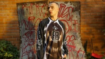 Homem-aranha-kings: modelo usando jaqueta e tênis em collab inspirada no Homem-Aranha, em frente a parede pichada