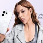Marina Sena segurando um smartphone OPPO branco, anunciada como a primeira Reno Girl da marca no Brasil.