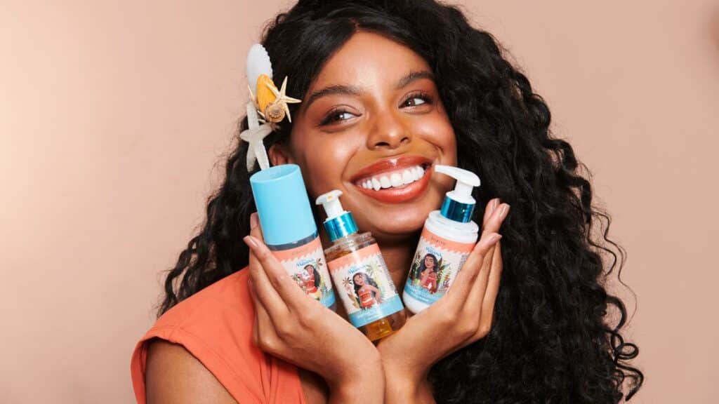 Mulher sorrindo segura frascos de skincare da coleção Miss Rôse inspirada em Moana