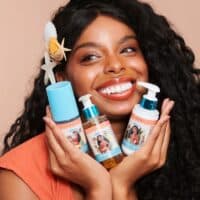 Mulher sorrindo segura frascos de skincare da coleção Miss Rôse inspirada em Moana
