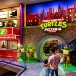 Fachada de pizzaria temática das Tartarugas Ninja em São Paulo, com iluminação neon e personagens em tamanho grande.