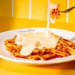 Prato do Spoleto com espaguete e molho de queijo sendo servido, em promoção com a Vigor